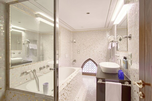 A bathroom with a glass-enclosed shower, a freestanding bathtub, and a vanity with a large mirror.