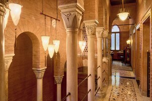 Un corridoio con archi, colonne e lampade a sospensione.