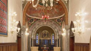 Um interior ornamentado com um candelabro, uma janela de vitrais e um soalho estampado.