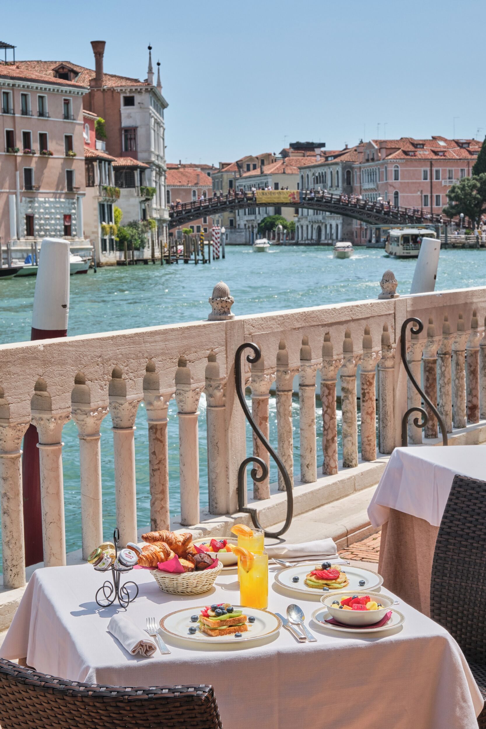 Mesa lista para el desayuno, con vista a un canal, edificios históricos y un puente.