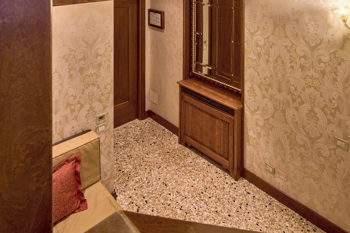 A room with a wooden ceiling, a chandelier, a wooden bench, and a patterned wall.
