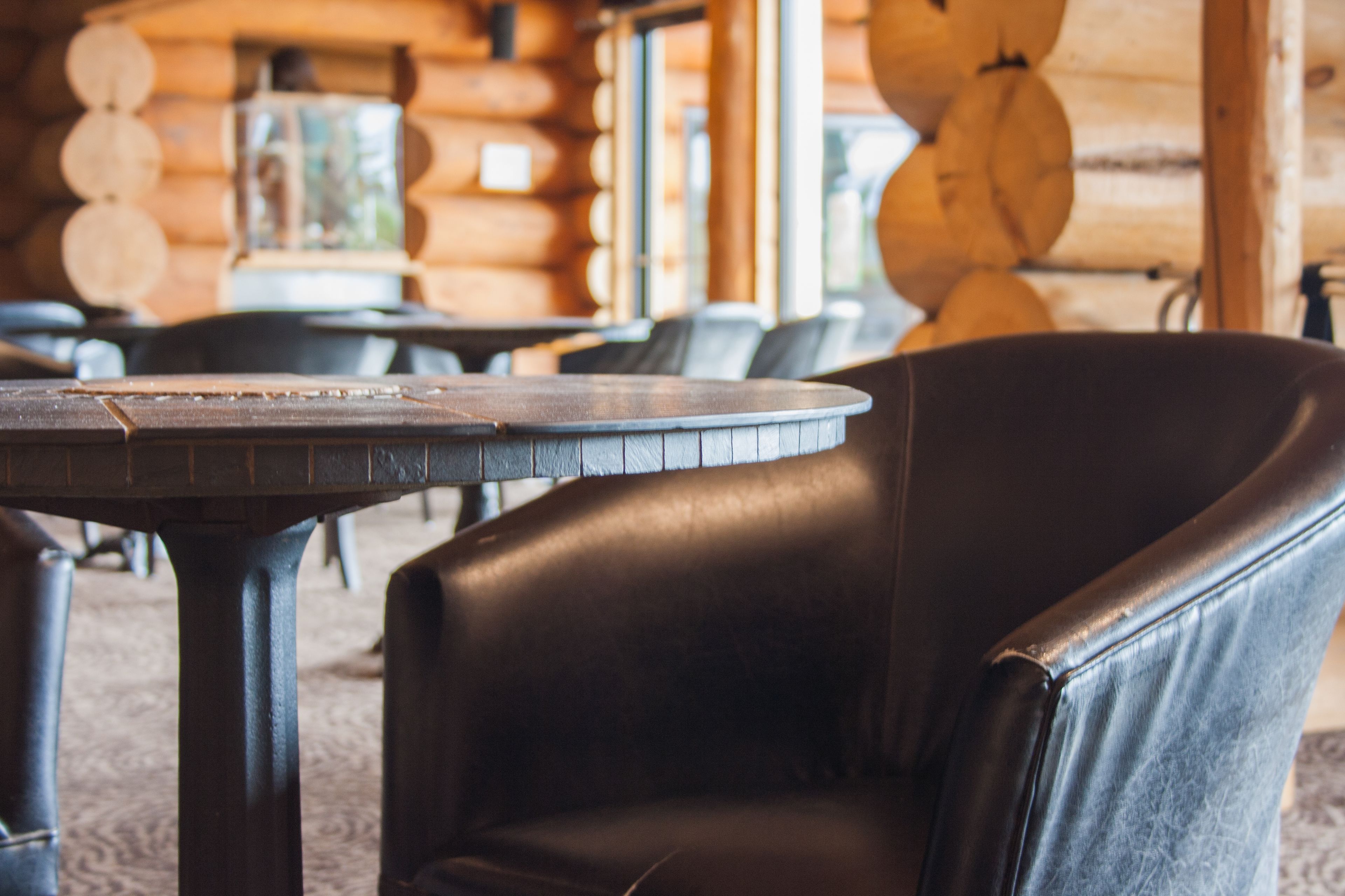 A wooden interior with a round table and a leather chair.