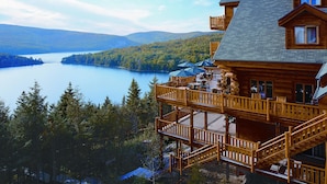 Une cabane en bois dotée d’un balcon donnant sur un lac et une forêt.