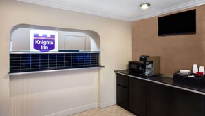 Zona de recepció d'hotel amb un senyal de Knights Inn, una màquina de cafè i un televisor de pantalla plana fixat a la paret.
