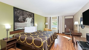 Een hotelkamer met een groot bed, een bureau, een televisie en uitzicht op een waterval door het raam.