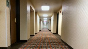 A long, narrow hallway with patterned carpet, white walls, and doors on both sides. - Quality Inn Junction City - Near Fort Riley (Junction City)