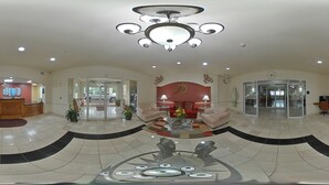 A spacious lobby with a modern chandelier, a reception desk, and a seating area with a coffee table.