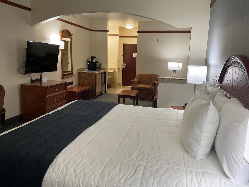 A hotel room with a bed, a TV, a desk, a chair, a lamp, and a mirror.