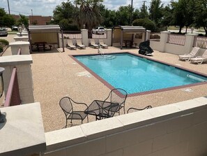 A swimming pool with lounge chairs and a covered seating area. - Budget Host Inn & Suites (Cameron)