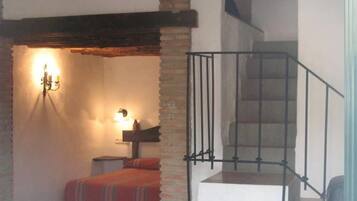 Ein Zimmer mit Treppe, einem Bett mit gestreifter Decke und einer Wandleuchte.