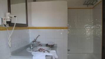 A bathroom with a sink, mirror, and a hairdryer on the counter.