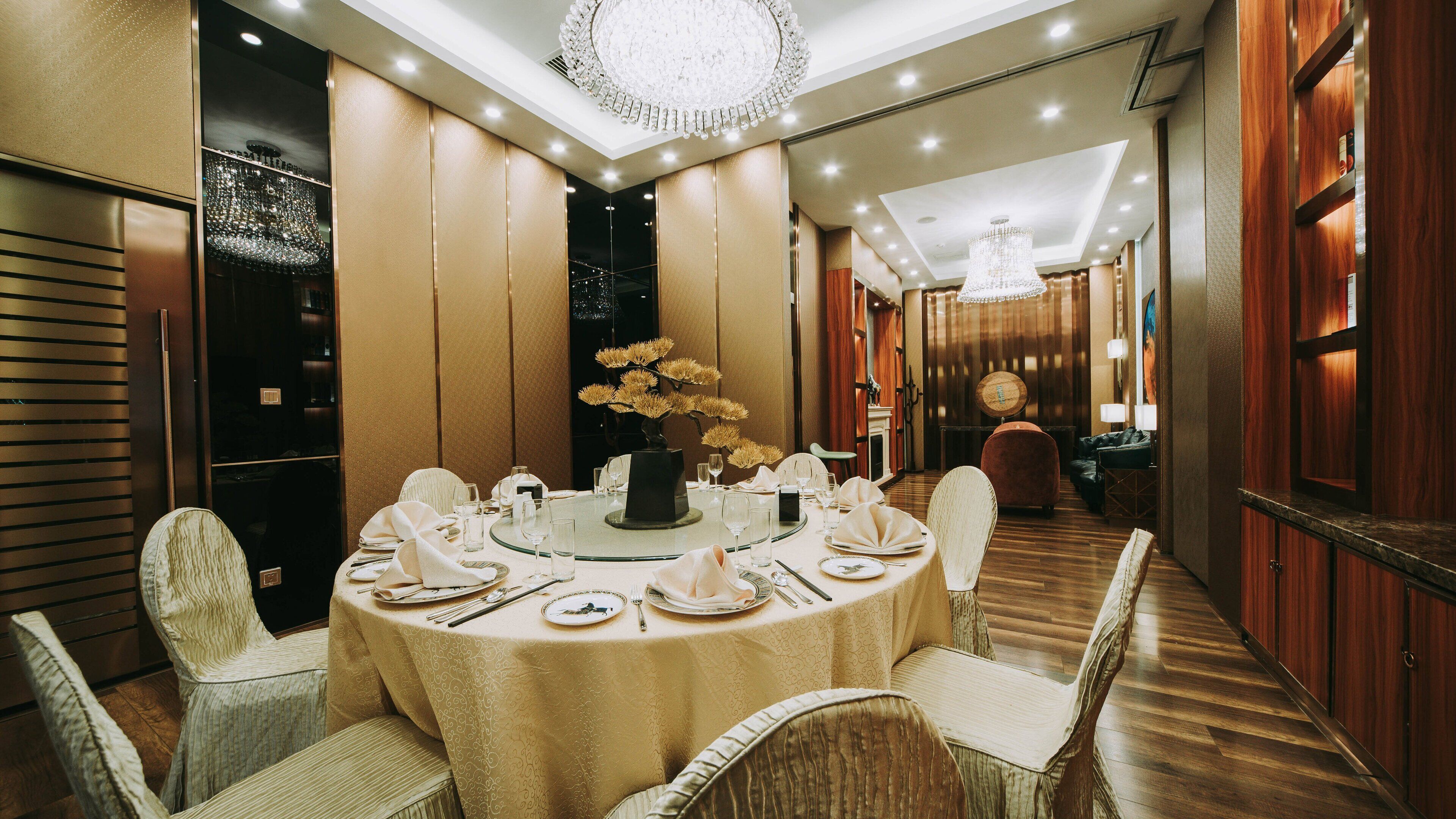 Una sala da pranzo formale con un tavolo rotondo apparecchiato per sei persone, circondato da sedie imbottite.