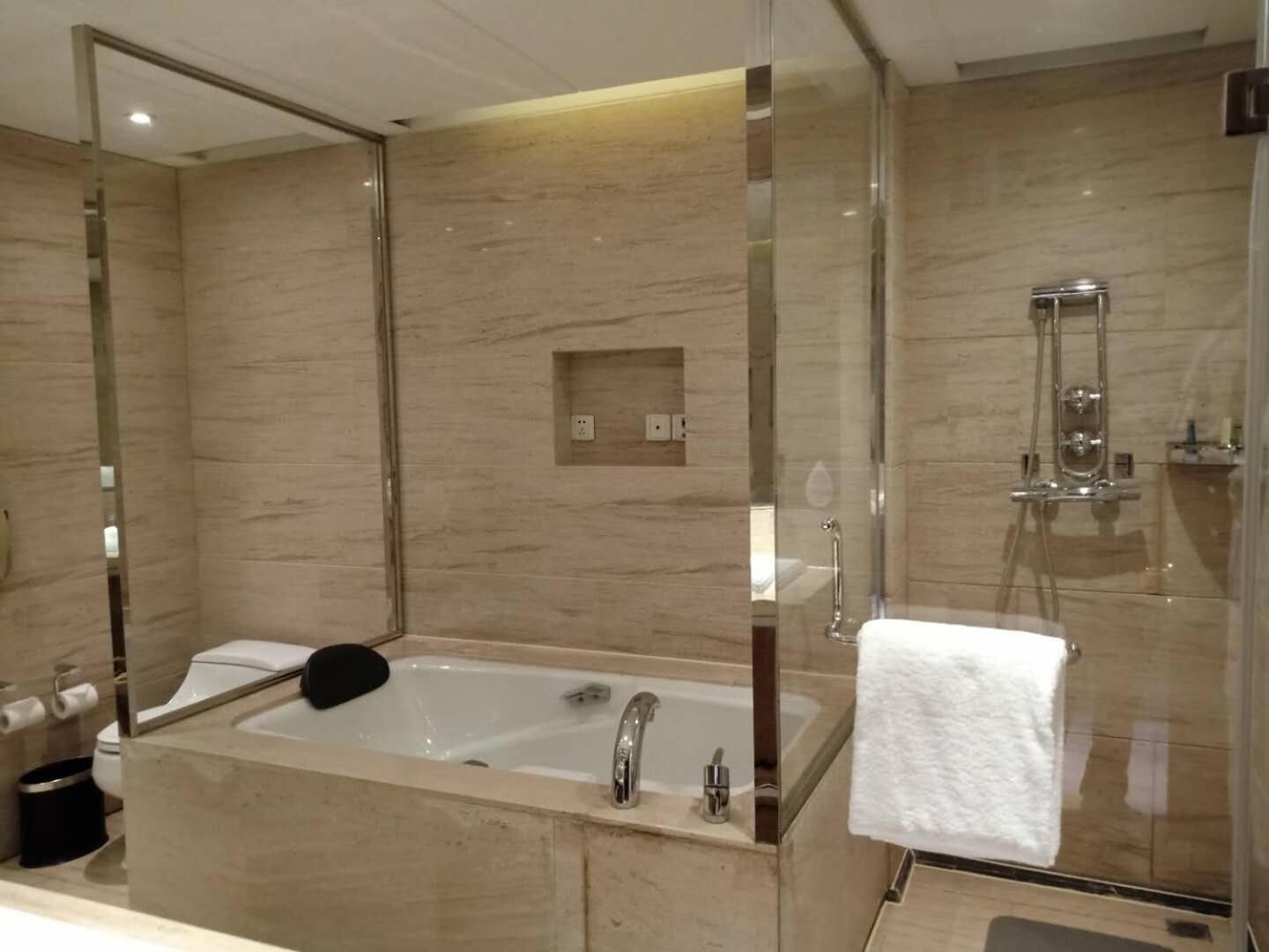 A modern bathroom with a large bathtub, a glass-enclosed shower, and a mirror above the sink.