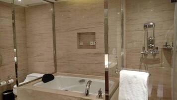 A modern bathroom with a large bathtub, a glass-enclosed shower, and a mirror above the sink.