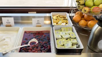 A food display with natural yogurt, fruit compote, butter, oranges, and apples.