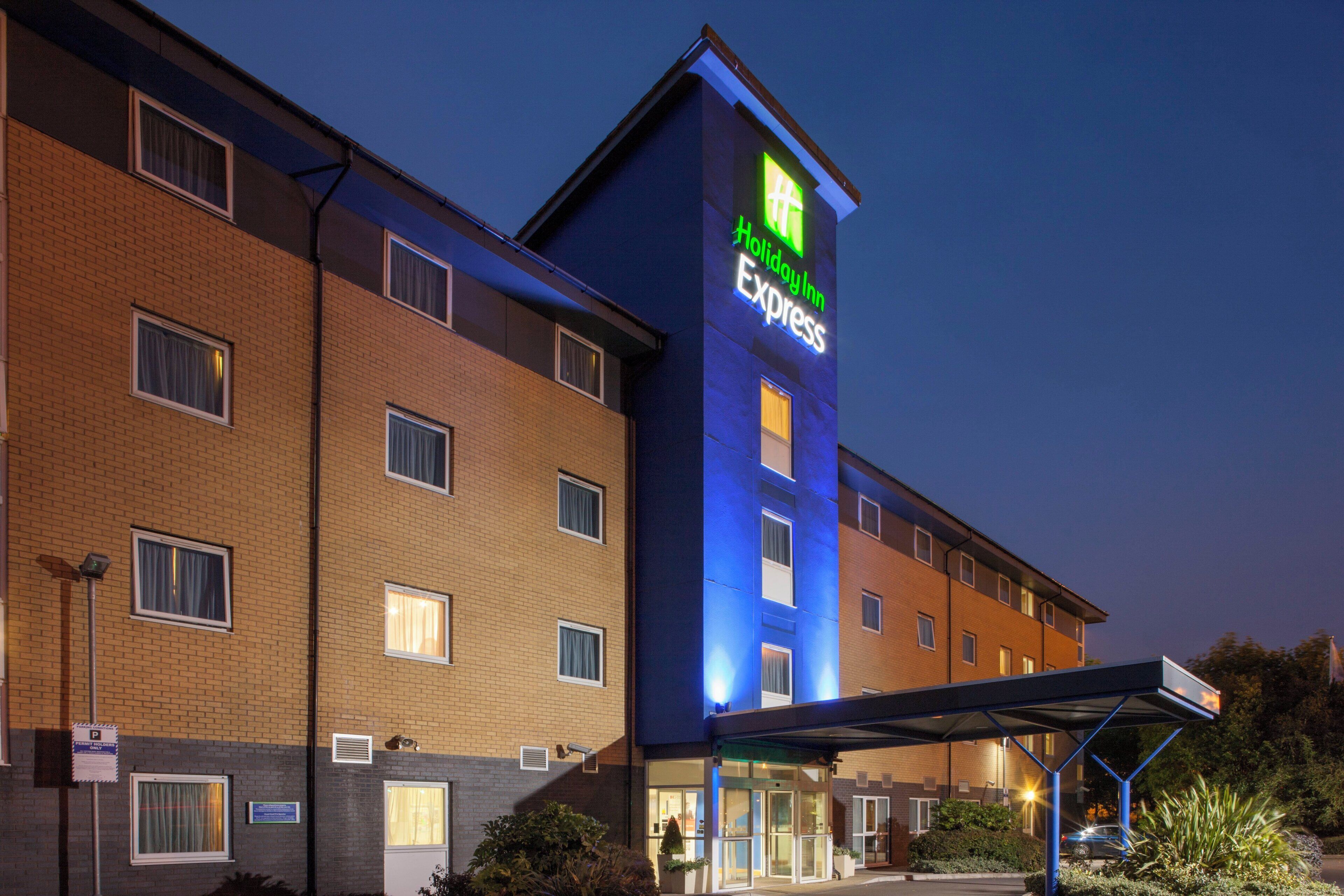 Edificio de Holiday Inn Express con fachada de ladrillo, múltiples ventanas y un área de entrada cubierta.