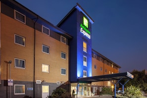 A Holiday Inn Express building with a brick facade, multiple windows, and a covered entrance area.