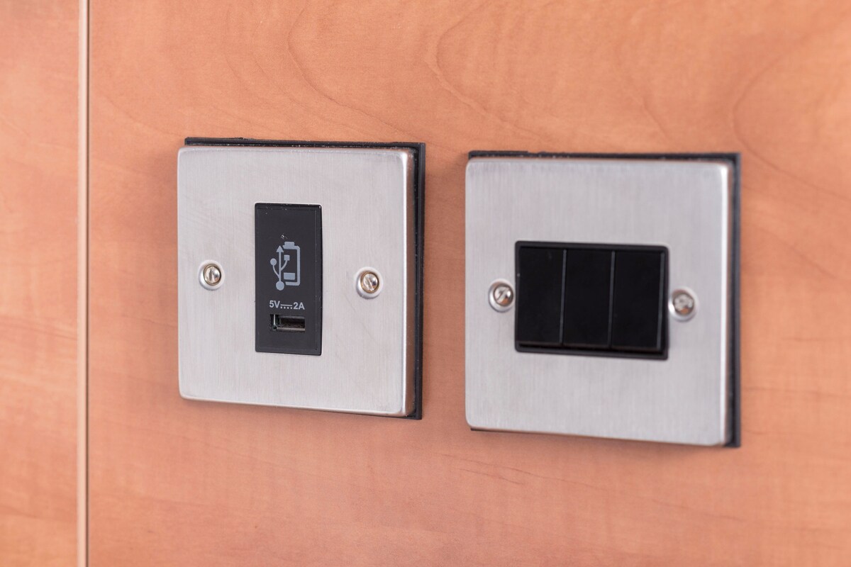 Two wall-mounted switches, one with a power symbol and the other with a black switch plate.