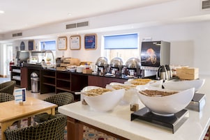 Ein Buffetbereich mit verschiedenen Speisen, einer Kaffeestation und Sitzgelegenheiten.