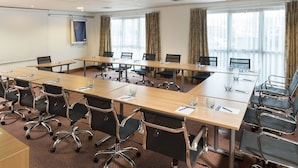 A conference room with long tables, chairs, and a projector screen. - Holiday Inn Express Birmingham Star City by IHG (Birmingham)