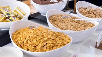 A buffet table with various food items including cereal, granola, and chocolate.