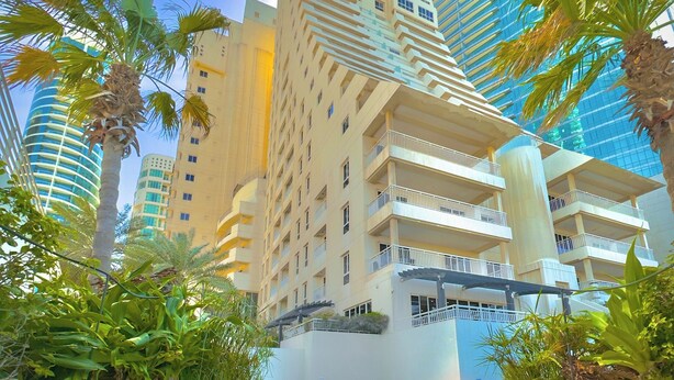 A swimming pool with tiled edges, surrounded by lush greenery and tall buildings in the background. - Mysk Al Fateh Bahrain (Manama)