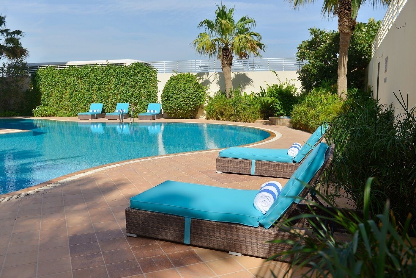 Una piscina al aire libre, sombrillas, tumbonas