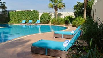 Una piscina al aire libre, sombrillas, tumbonas