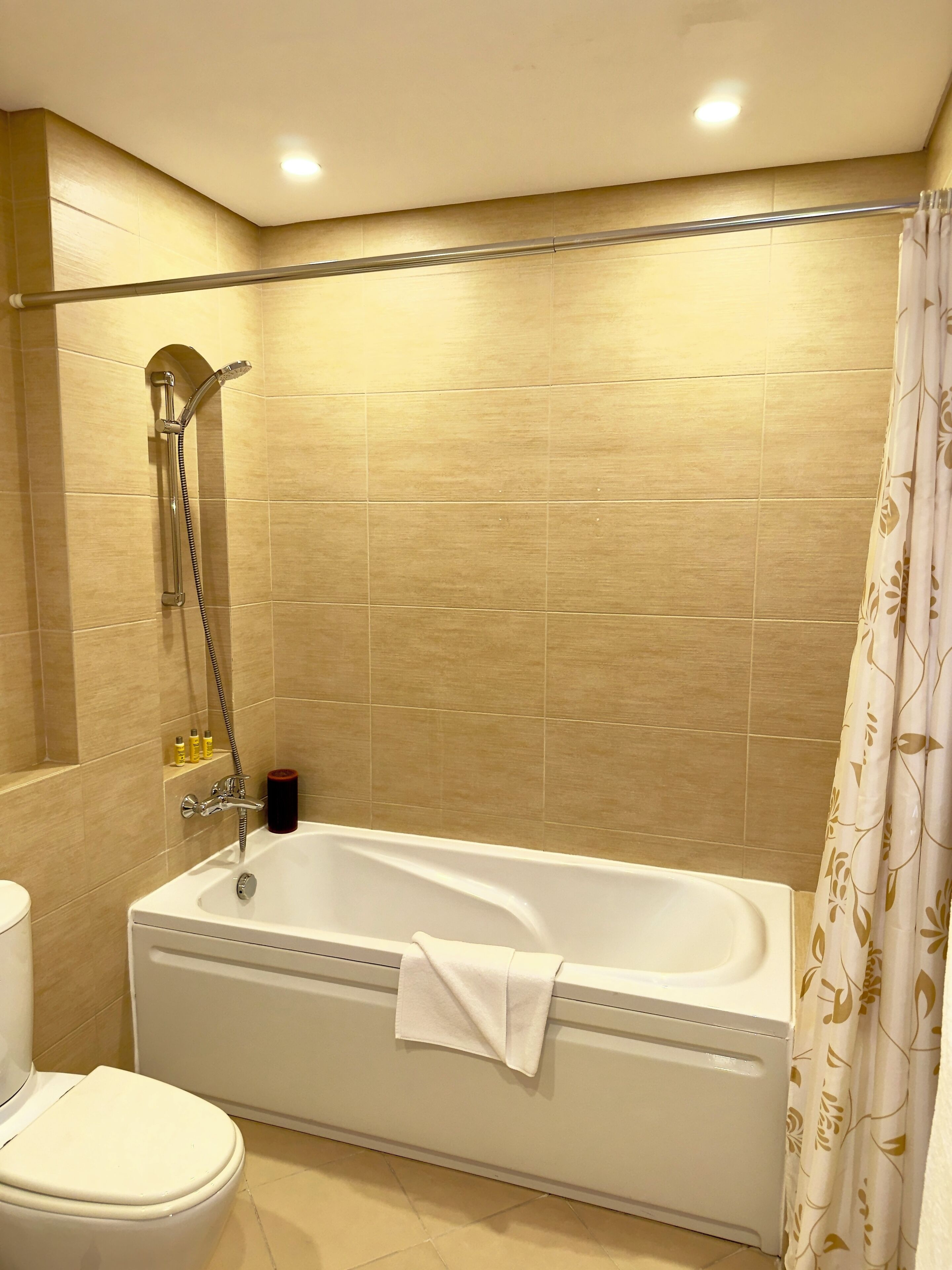 Un baño con bañera, ducha, inodoro y paredes con azulejos.
