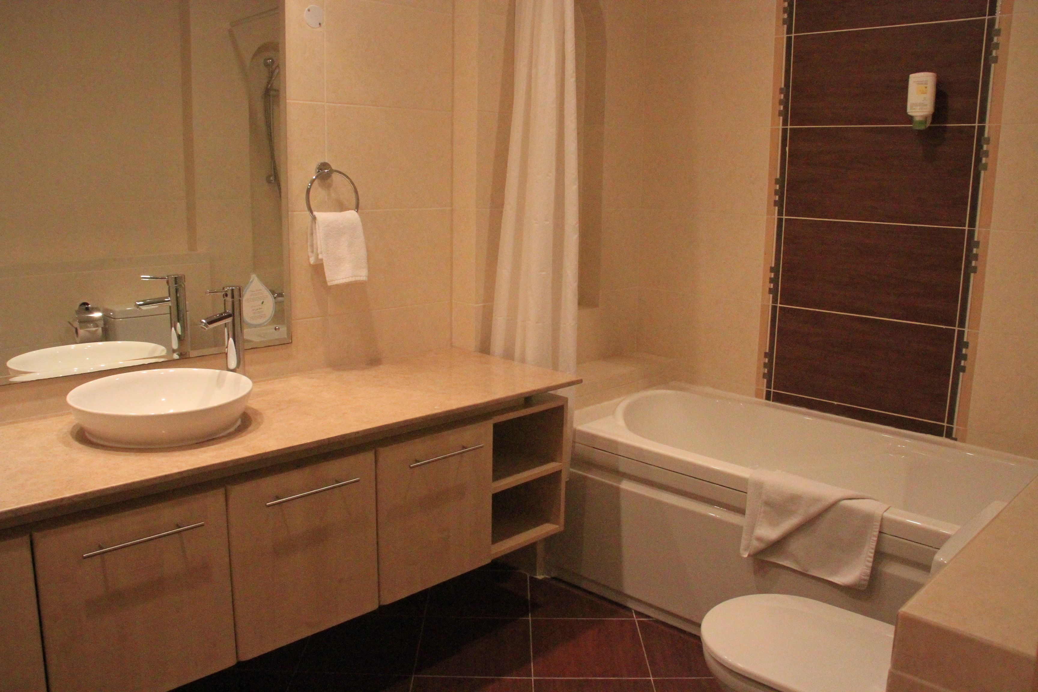 A bathroom with a sink, mirror, vanity, and a bathtub.