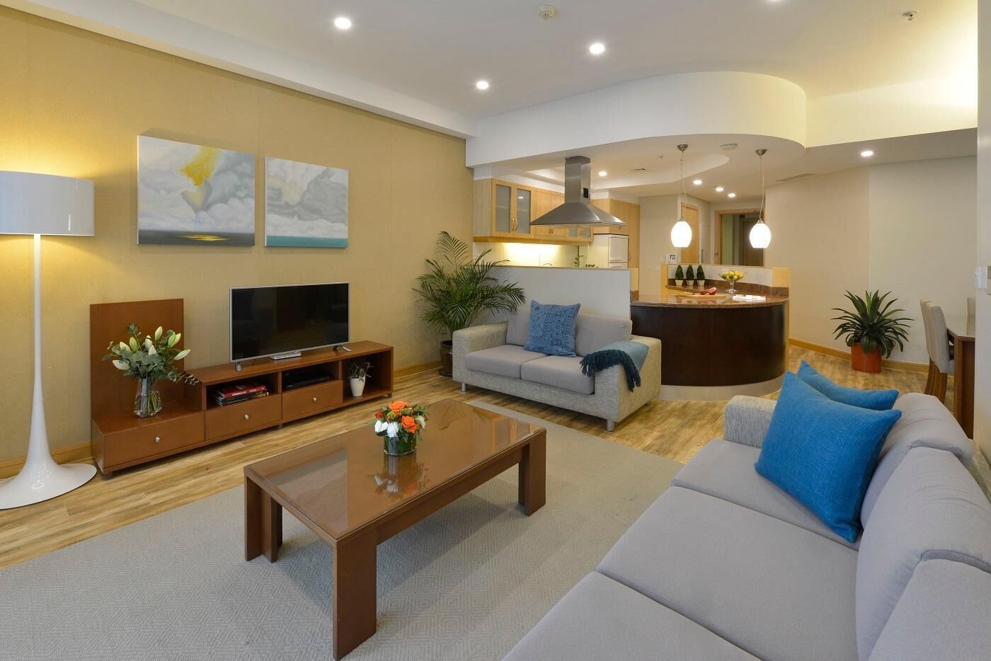 A modern living room with a sofa, coffee table, TV, and artwork on the wall.