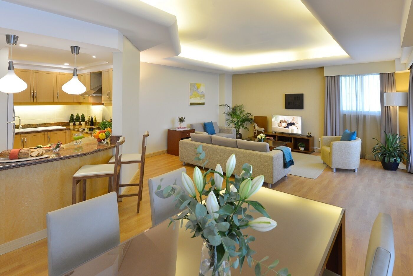 Una sala de estar moderna con sofá, televisión y comedor.