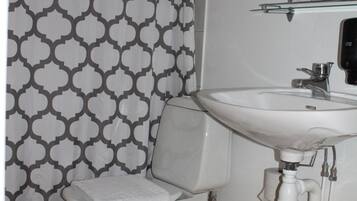 A bathroom with a toilet, sink, and shower curtain.