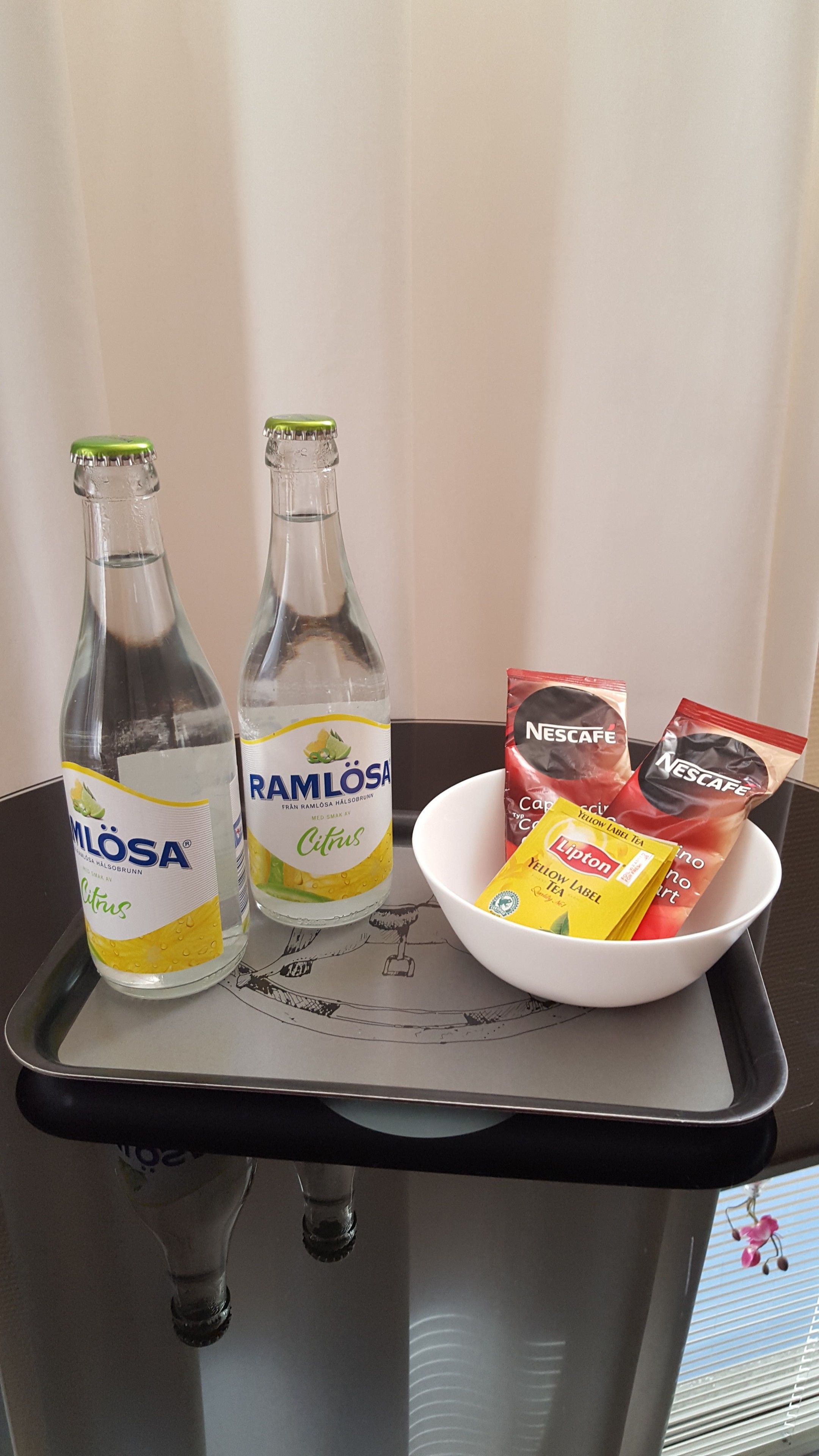Two bottles of Ramlosa citrus drink, a bowl of Nescafe coffee, and Lipton tea on a tray.