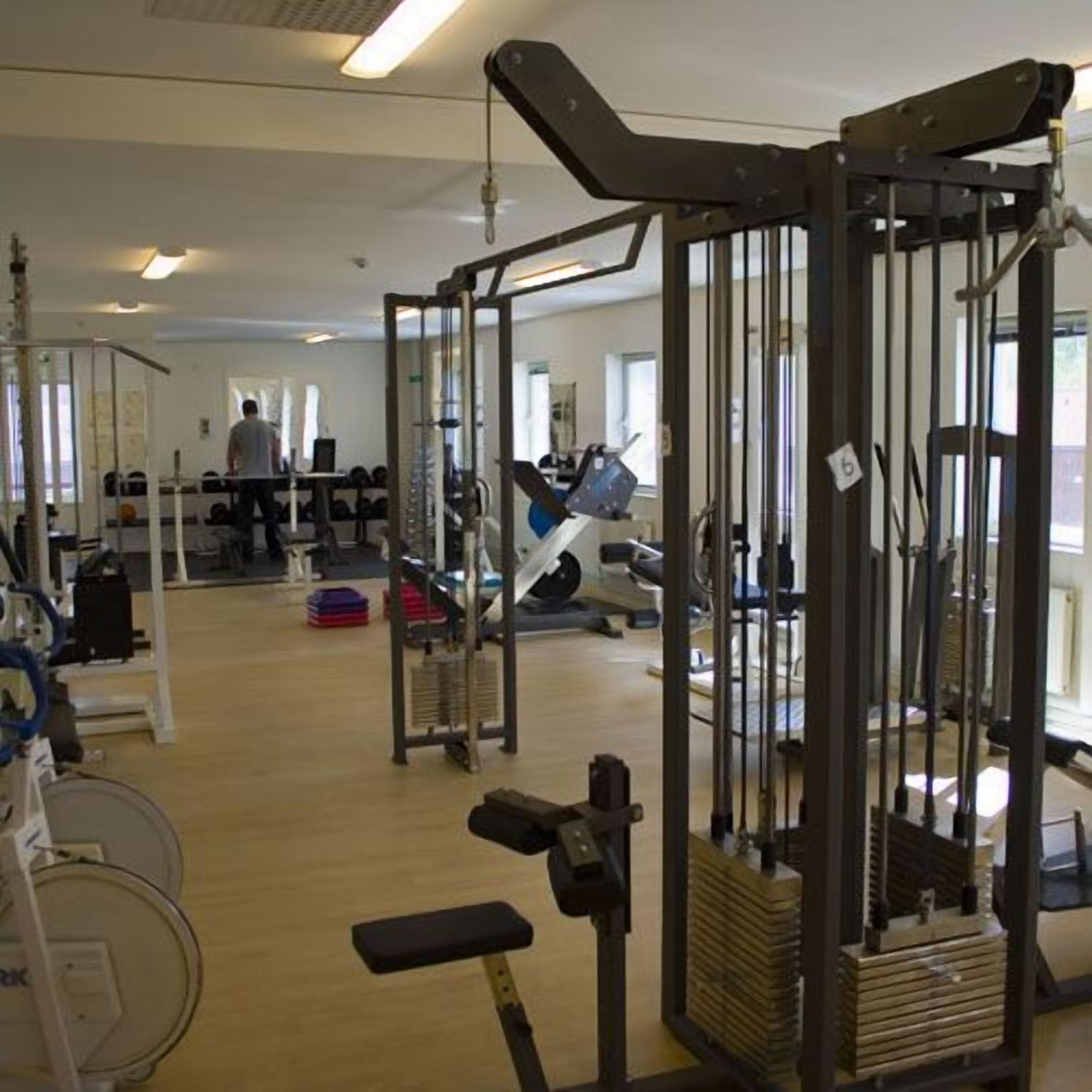 Un gimnàs amb diferents aparells d'exercici, com ara una barra de squats, bancs i peses.