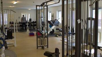 Une salle de sport équipée de divers appareils d’entraînement, notamment un support à squats, des bancs et des poids.