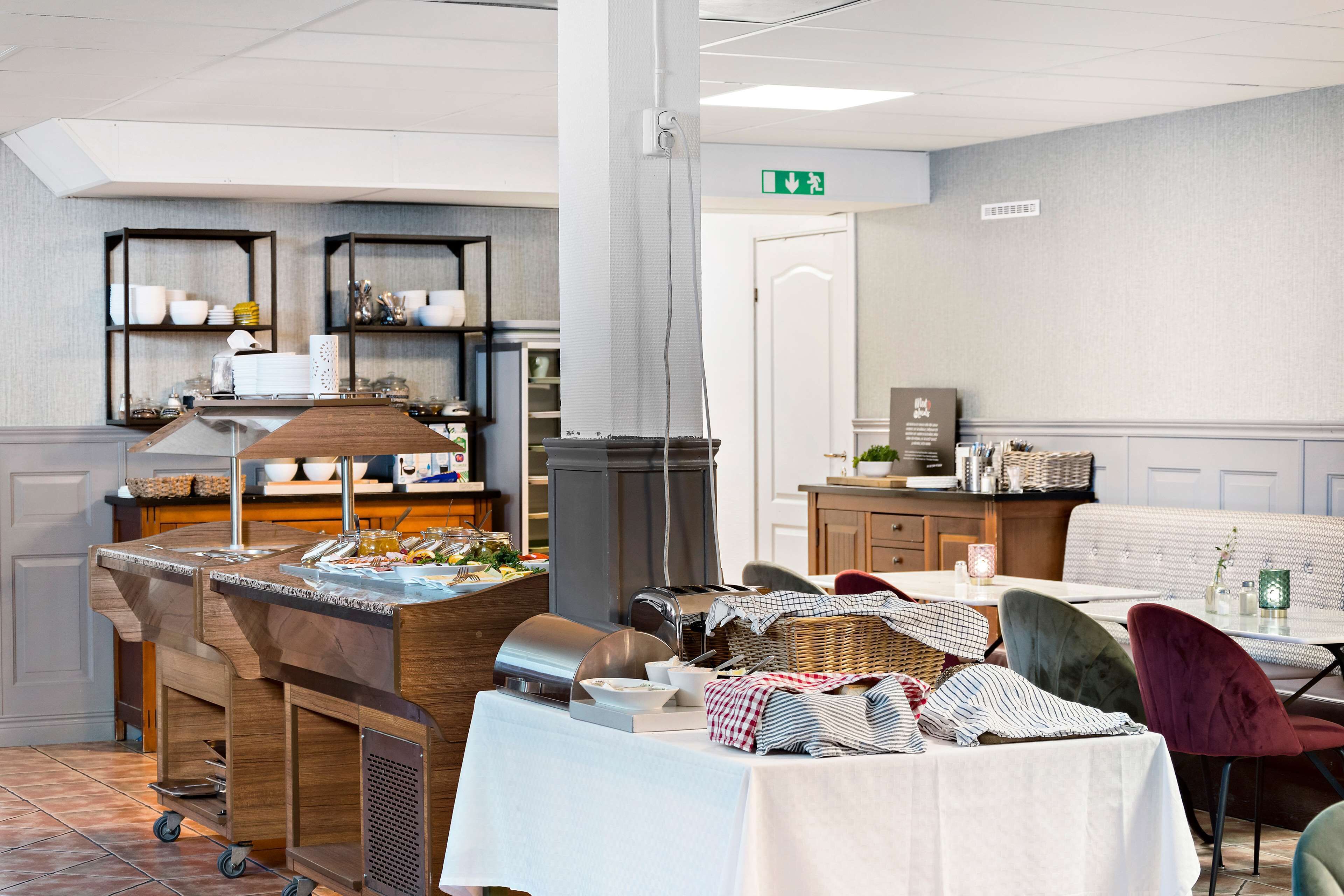 A buffet setup with a wooden counter, a coffee machine, and a seating area with cushioned chairs.