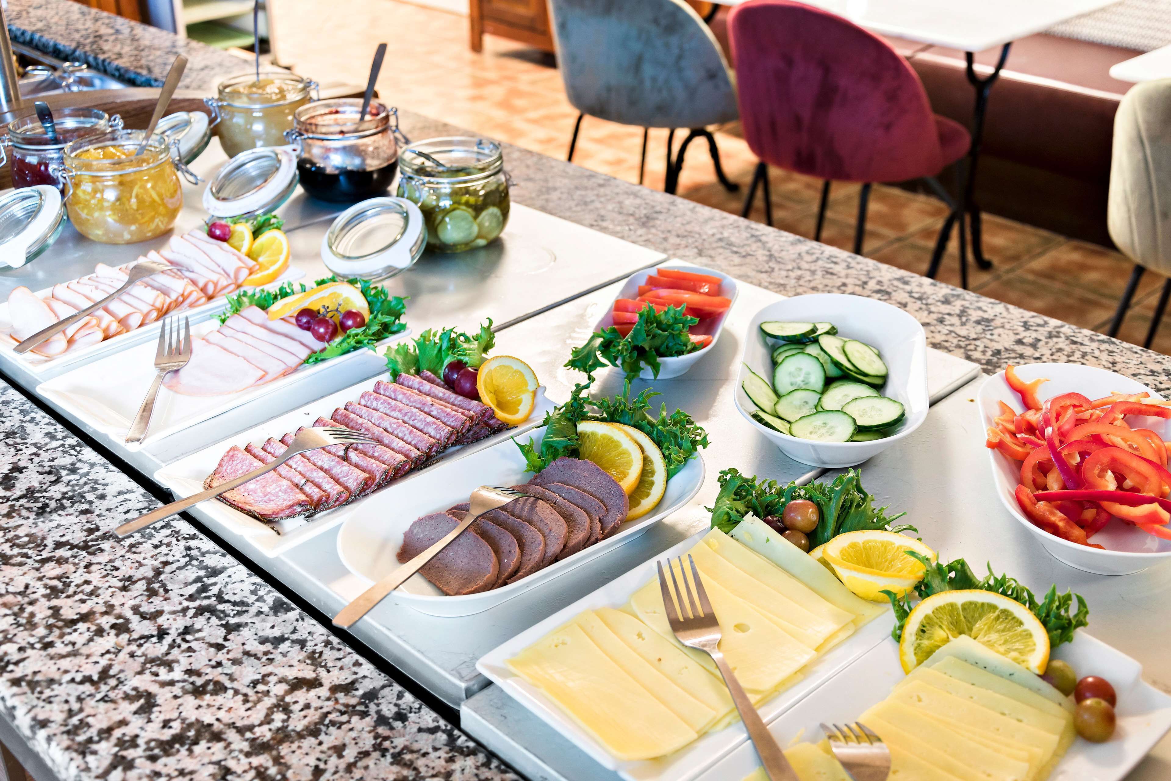 Una mesa de buffet con diversos alimentos, incluyendo carnes, quesos y verduras.