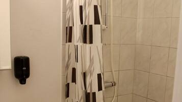 Un baño con inodoro, lavamanos, ducha y secamanos.