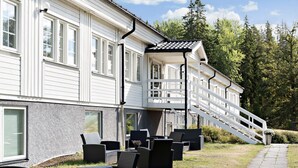 Valkoinen rakennus, jossa on katettu ulkoalue istumista varten ja portaikko, joka johtaa parvekkeelle.