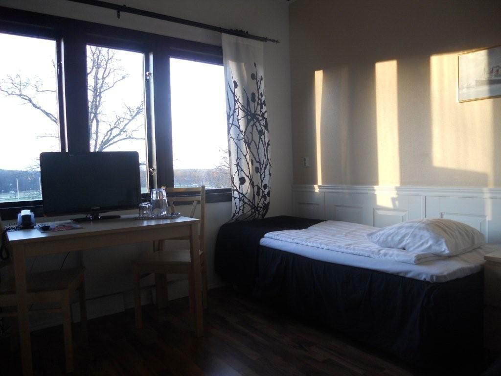 A room with a bed, a desk with a computer, and a window with curtains.