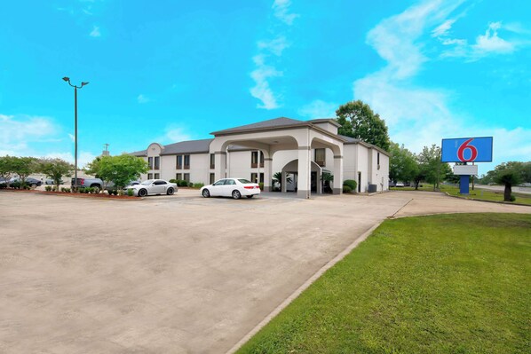 A hotel with a large parking lot, a covered entrance, and a sign indicating it is a Motel 6. - Motel 6 Abbeville, LA (Abbeville)