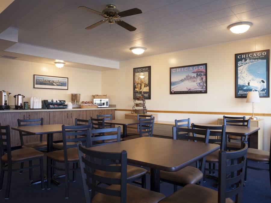 Un restaurante con varias mesas y sillas, una barra con una máquina de café y decoraciones en la pared, incluyendo carteles.