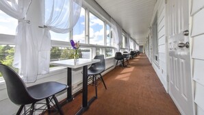 A corridor with white walls, large windows, and black chairs. - Auberge Hôtel Spa Watel (Sainte-Agathe-des-Monts)