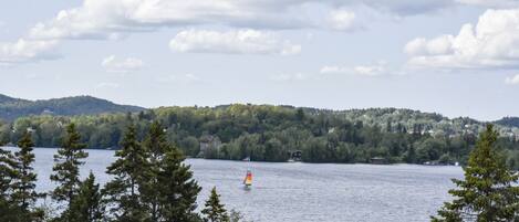 A lake with a sailboat, surrounded by trees and hills.