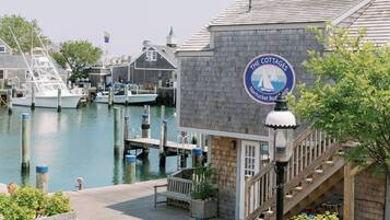 A waterfront property with a dock, a sign for 'The Cottages Nantucket Boat Haven,' and a staircase leading to a wooden deck.