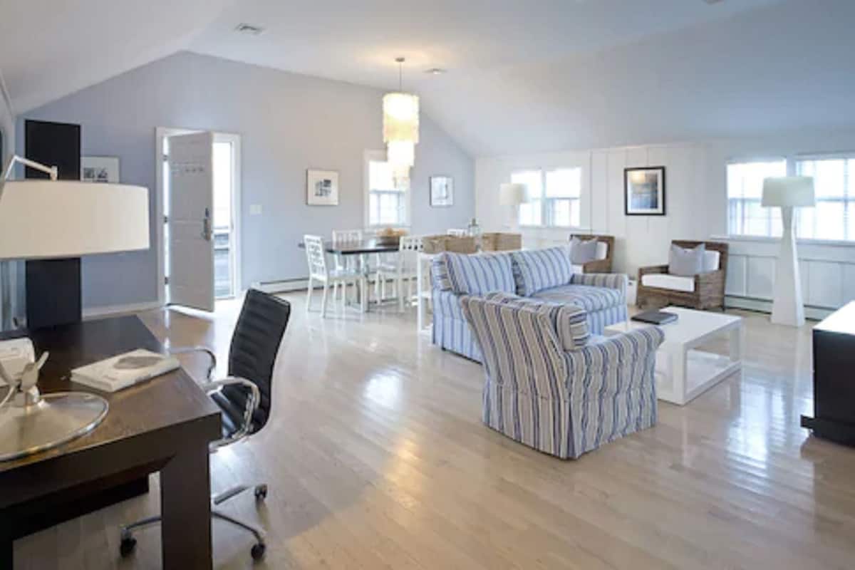 A spacious living room with a high ceiling, a dining area with a table and chairs, and a cozy seating area with a sofa and armchairs.