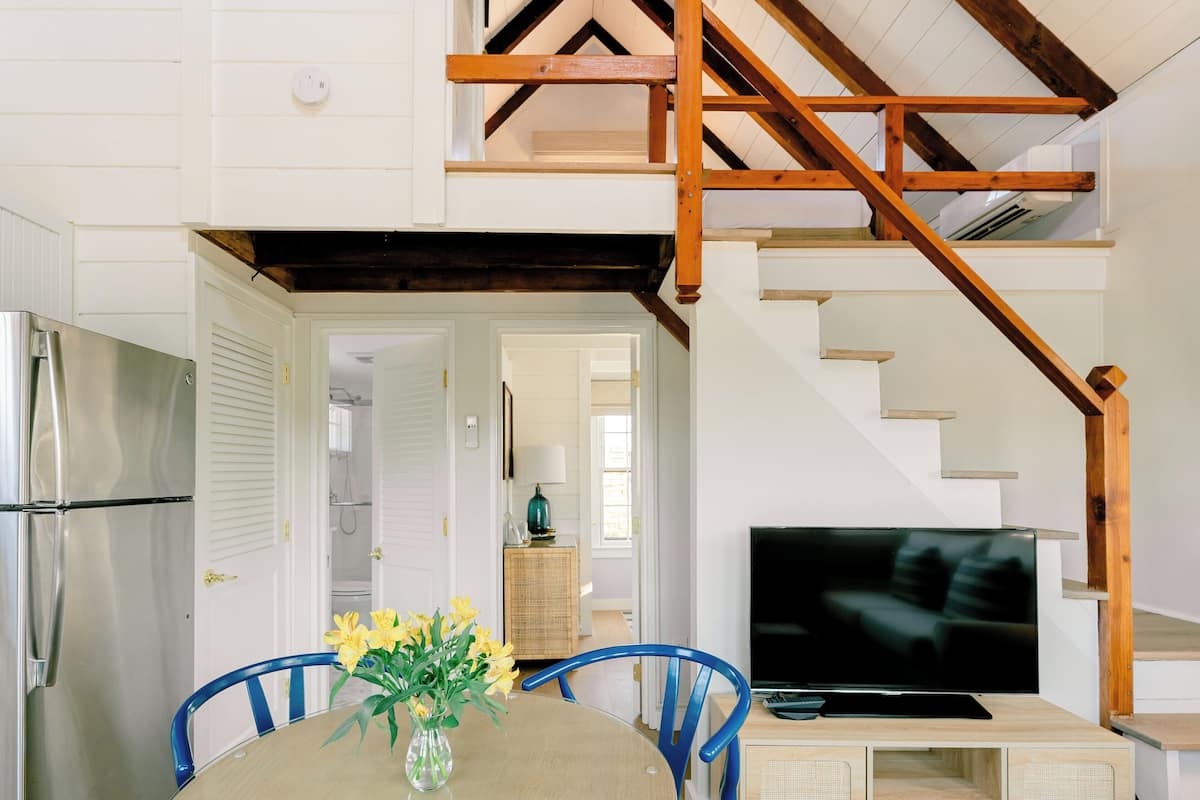 A dining area with a table, chairs, and a vase of flowers.