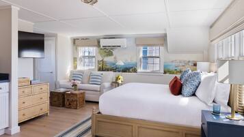 A bedroom with a large bed, a TV, a dresser, and a window with a view of a landscape.