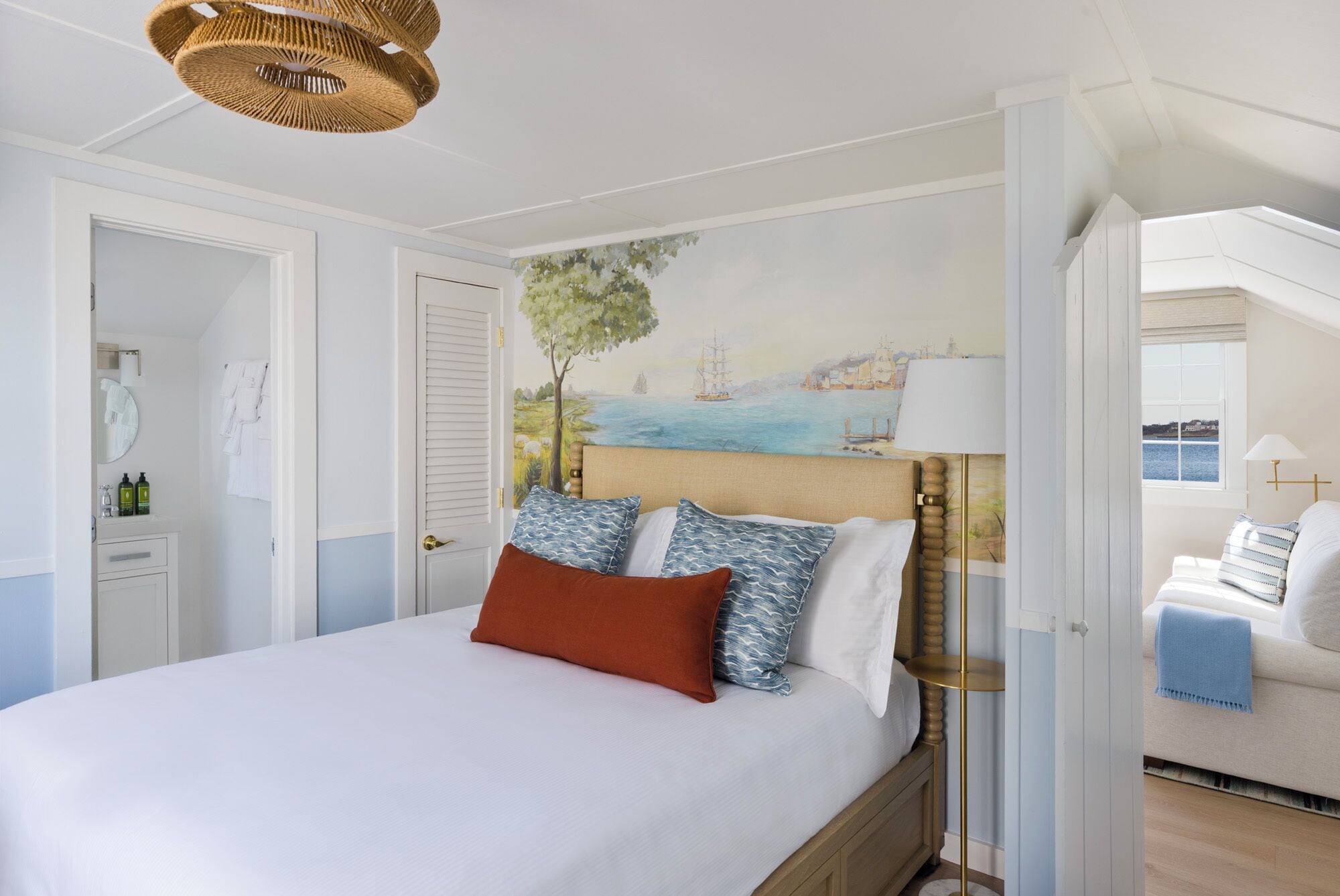 A bedroom with a bed, a nightstand, a lamp, and a painting on the wall.